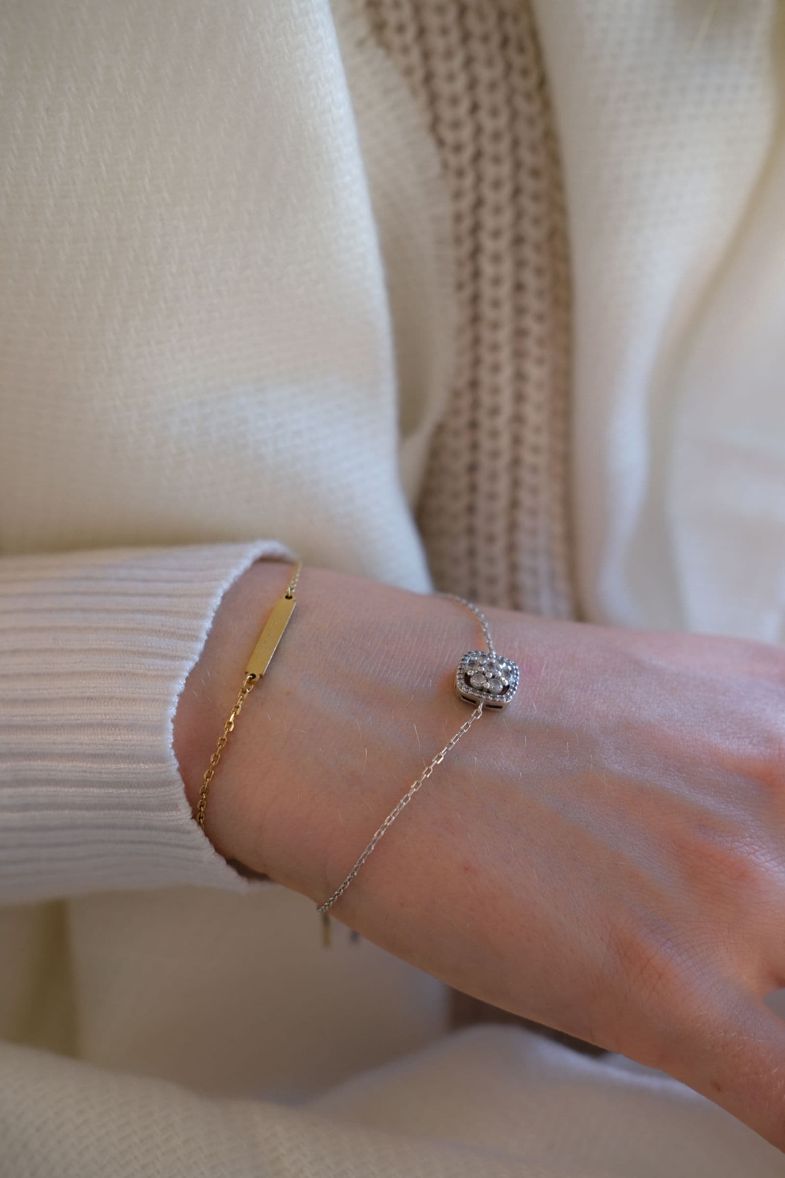 A gold bar bracelet and a silver-tone chain bracelet worn together on one wrist.