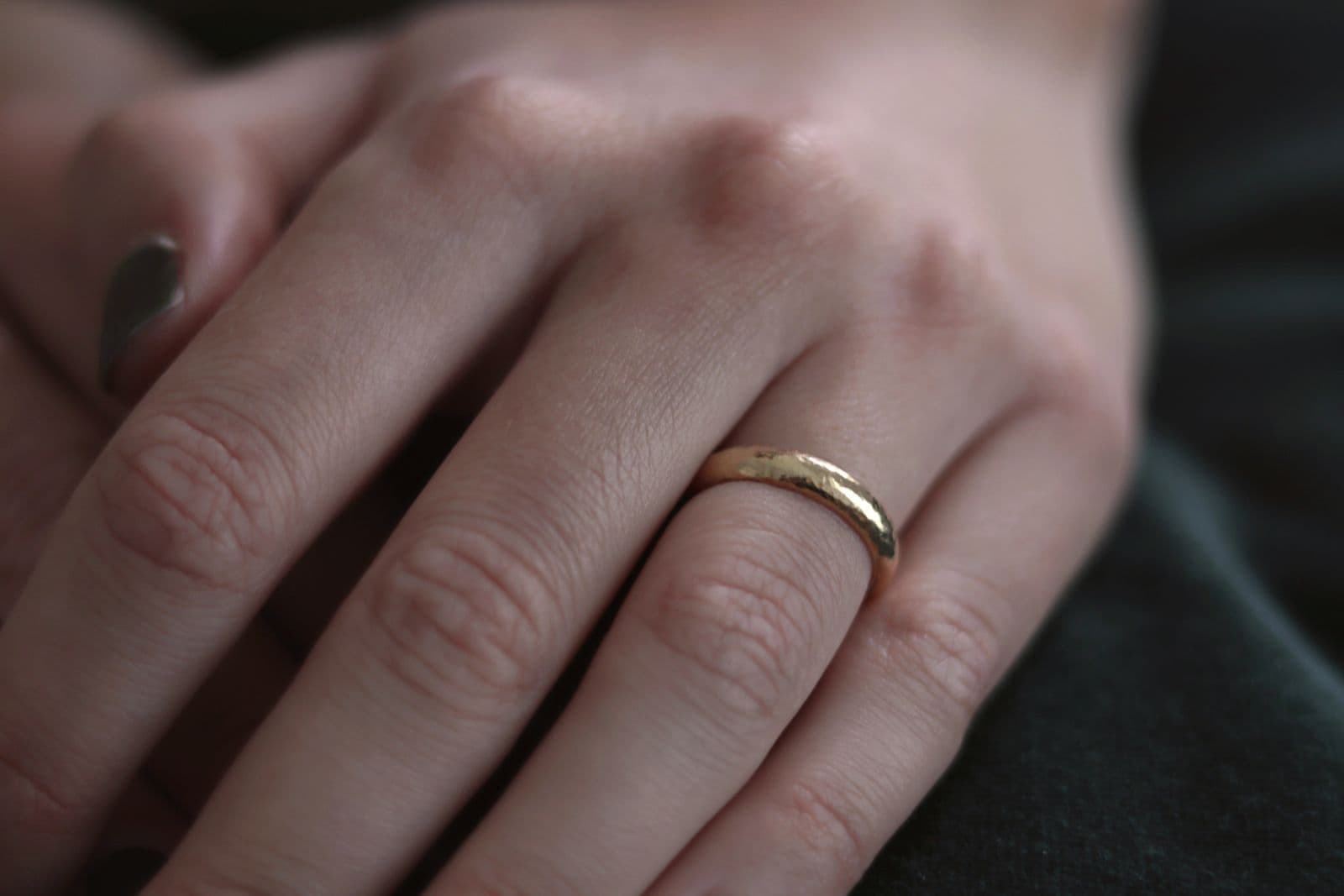 A plain gold band on a finger, photographed close enough to show the skin around it.